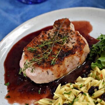 Pork Chops with Cherry Sauce topped with thyme sprigs.