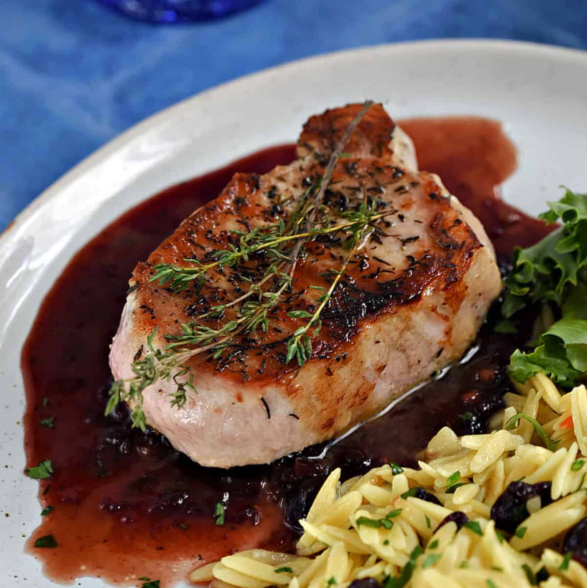 Pork Chops with Cherry Sauce topped with thyme sprigs.