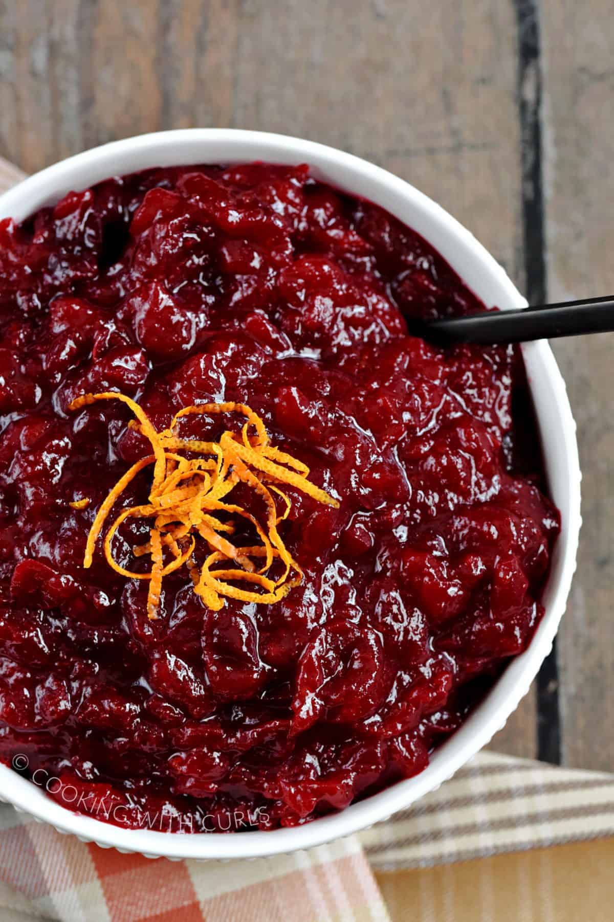 Looking down on a bowl of orange amaretto cranberry sauce garnished with strips of orange zest.