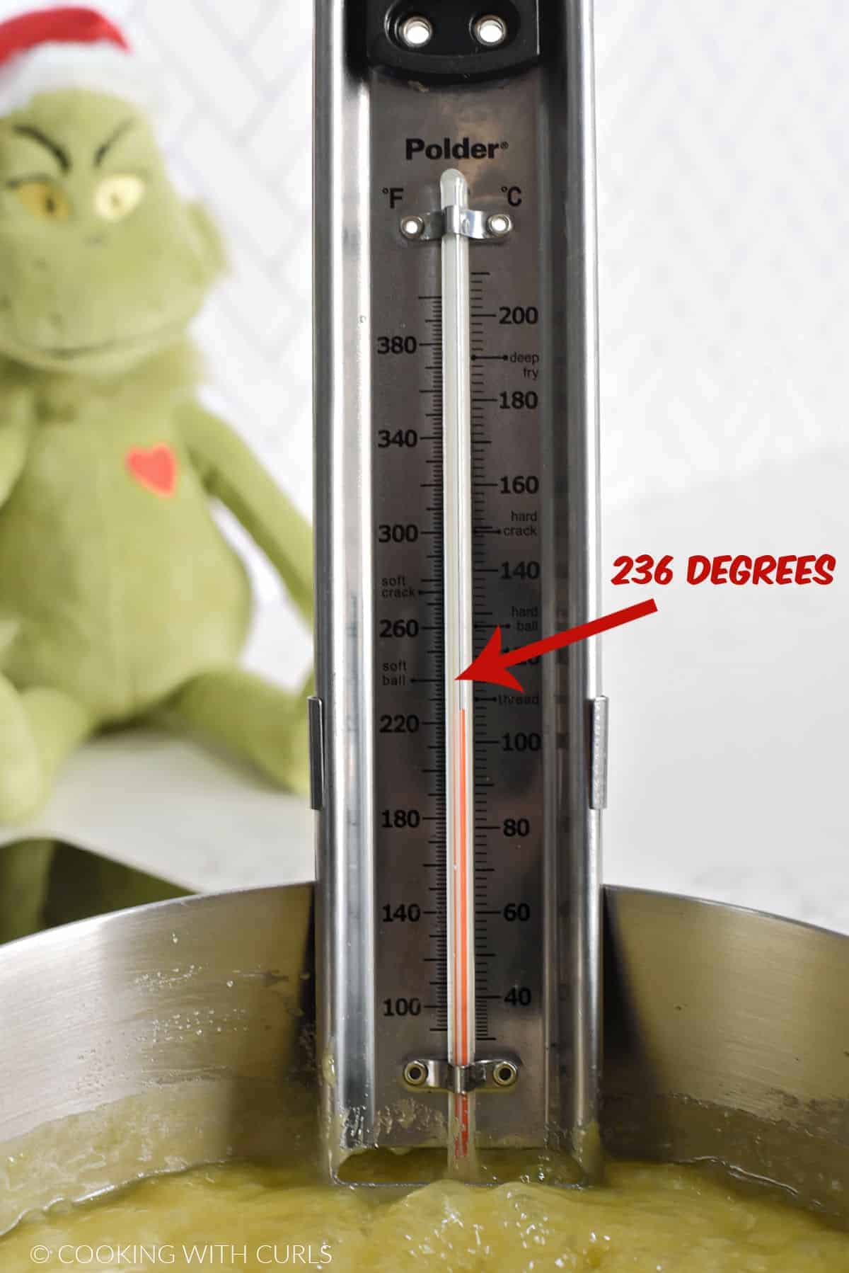 Candy thermometer in a saucepan of bubbling fudge with red arrow and 236 degrees on the edge. 
