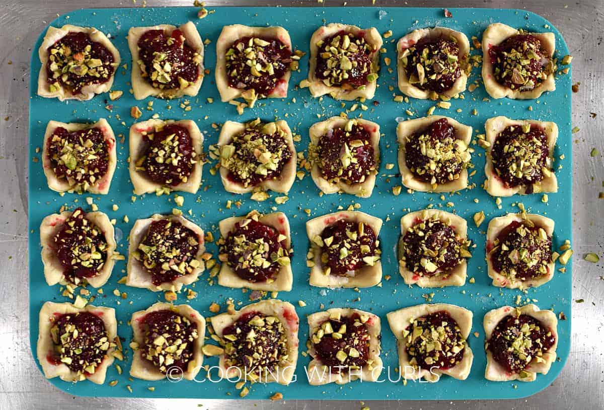 Chopped pistachios on top of the cranberry brie puff pastry bites in a mini muffin pan. 