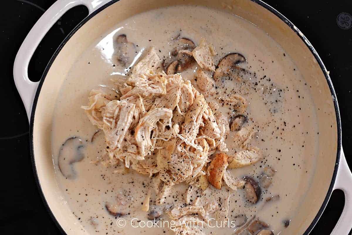 Chunks of chicken in a creamy mushroom sauce in a skillet. 