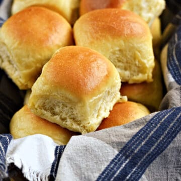 Quick Yeast Dinner Rolls piled high in a blue and white towel lined basket.