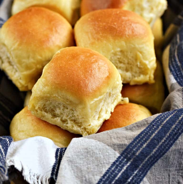 Quick Yeast Dinner Rolls piled high in a blue and white towel lined basket.