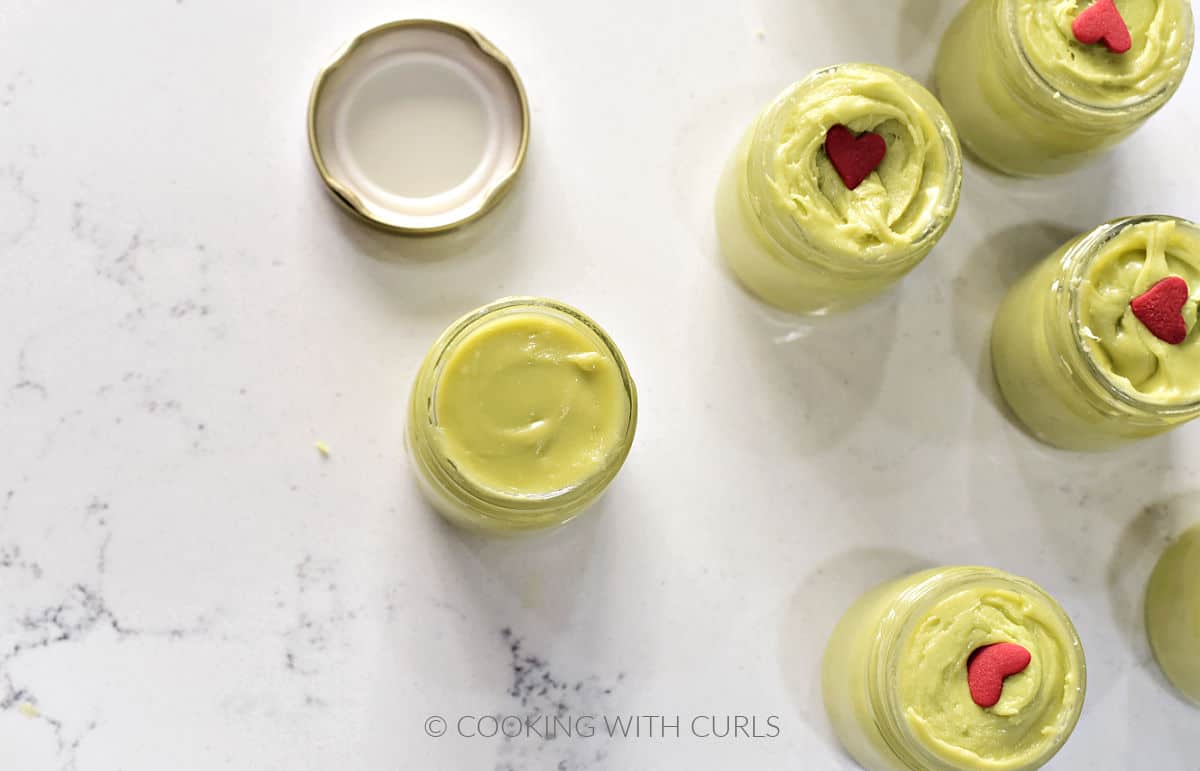 Green fudge poured into six tiny jars with tiny red hearts in the center. 