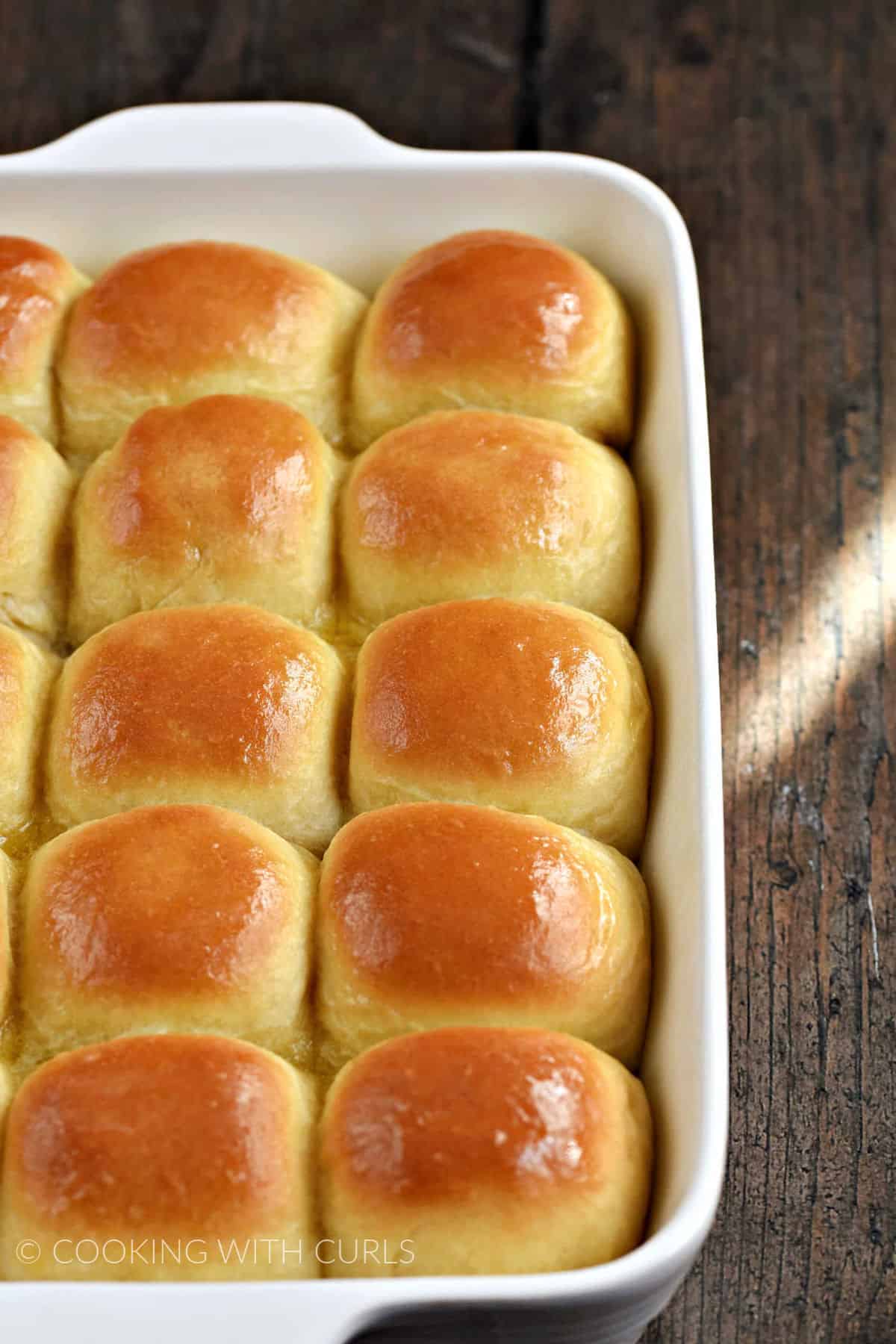 Fifteen shiny dinner rolls in a white baking dish.