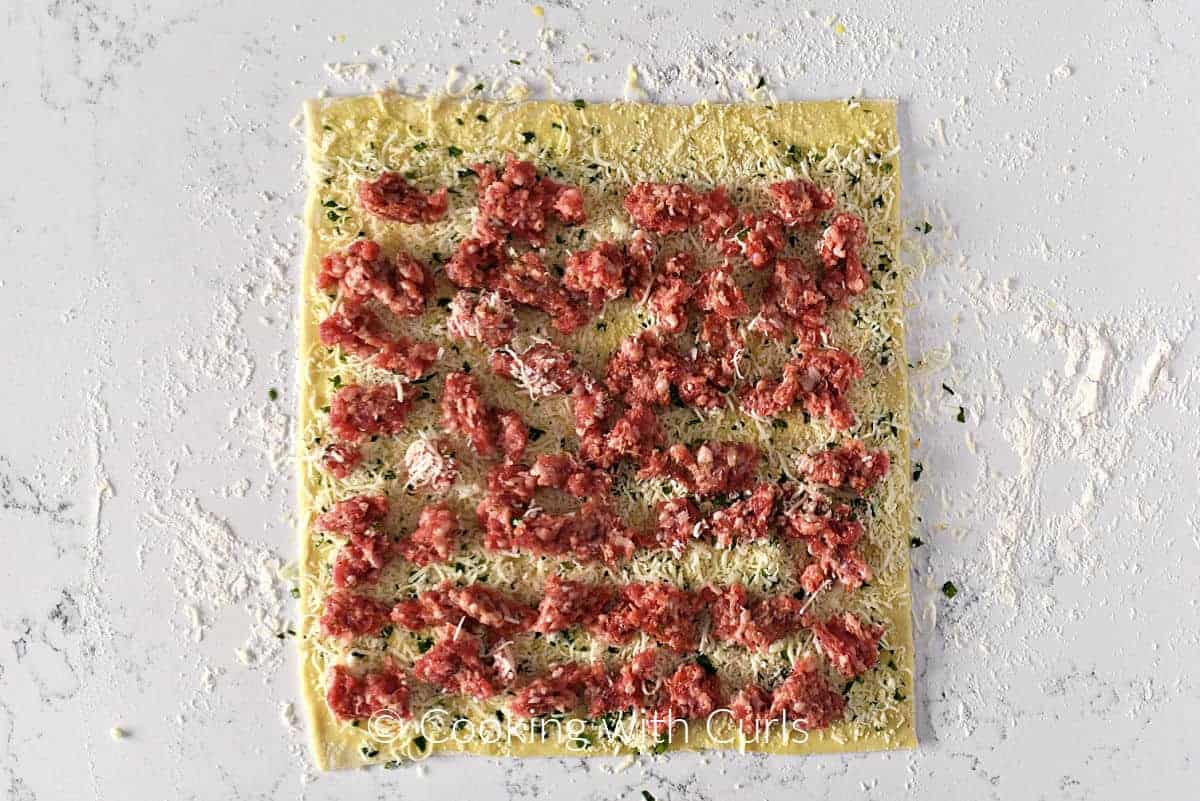 Raw bulk sausage spread over the cheese mixture topped puff pastry sheet. 