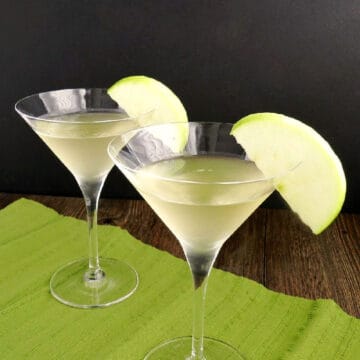 Two Caramel Apple Martinis with an apple slice garnish.