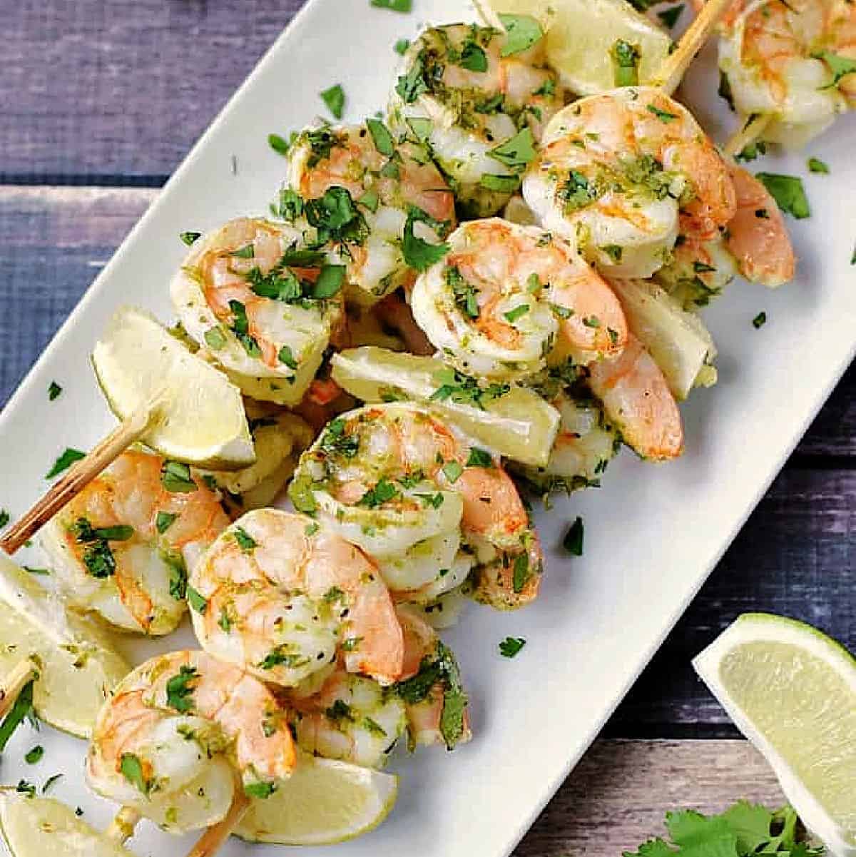Cilantro Lime Shrimp on skewers stacked up on a platter.