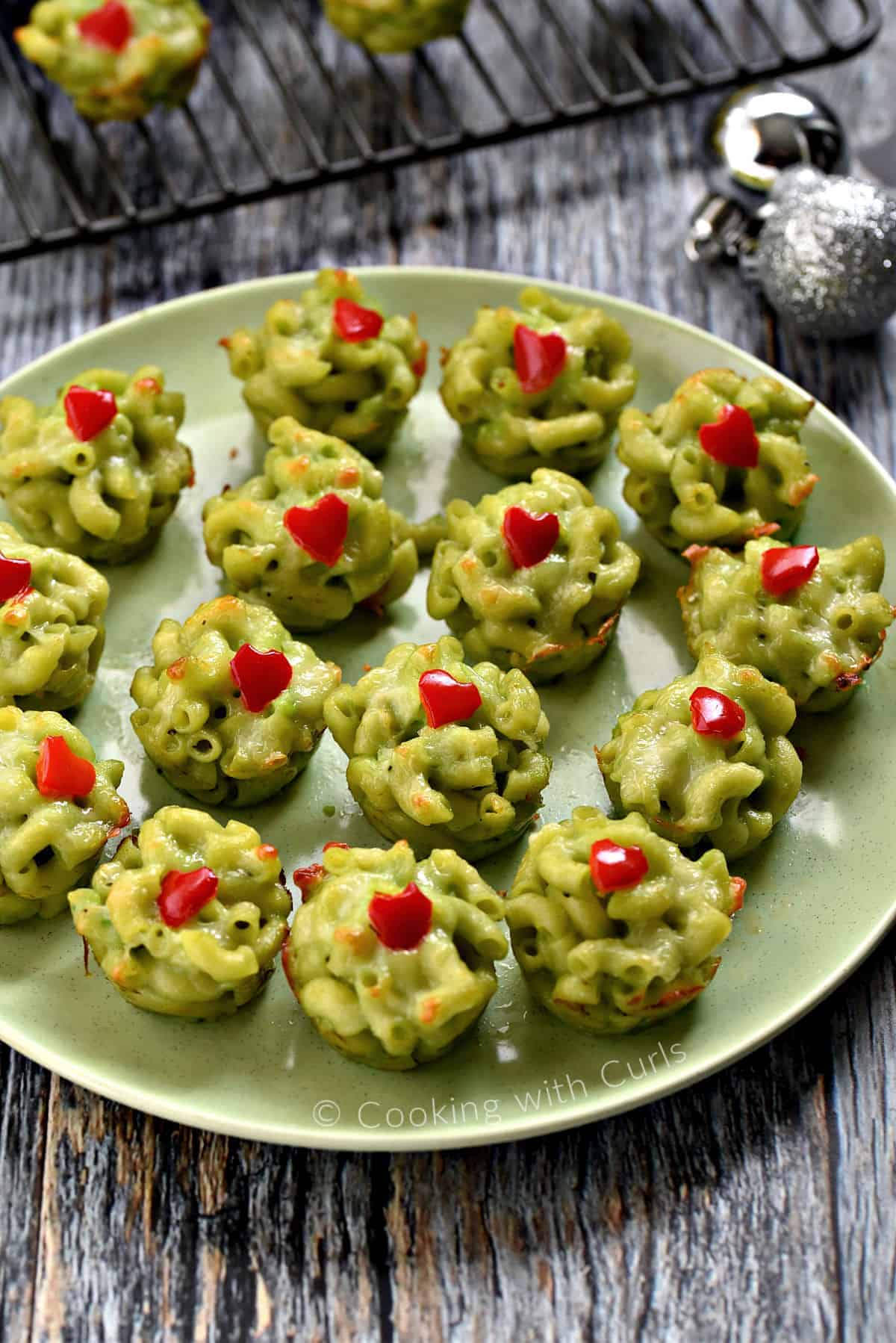 Fifteen Grinch green Mac and Cheese Bites on a green plate.