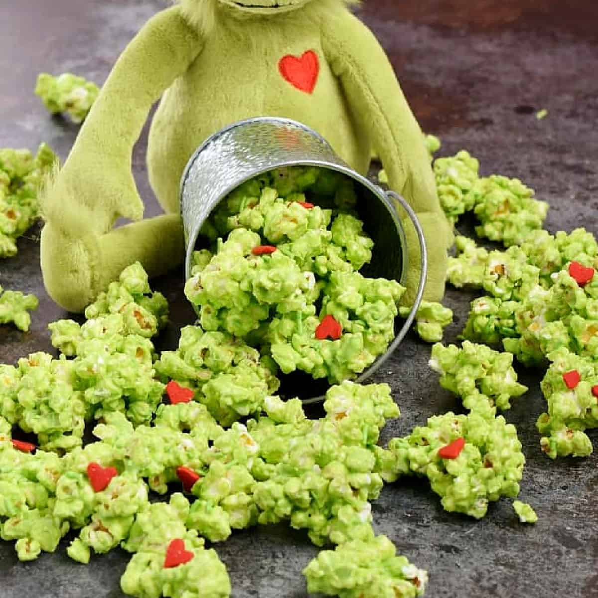 Grinch Popcorn with red hearts spilling out of a metal bucket.