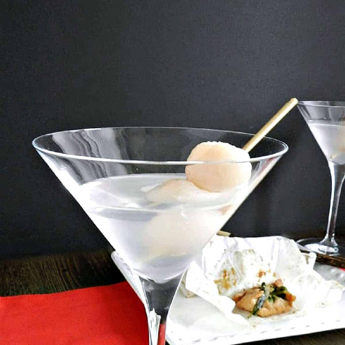 Martini garnished with three lychees on a toothpick.