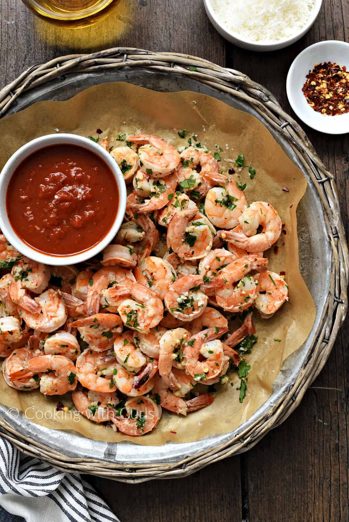 Oven Baked Garlic Shrimp on a serving platter with a bowl of marinara sauce. 
