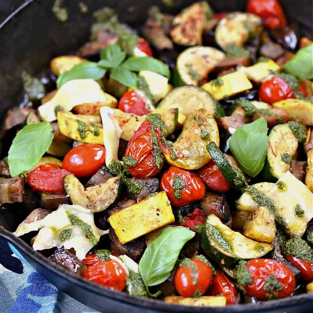 Chopped zucchini, squash, eggplant, and cherry tomatoes charred on the grill in a cast iron skillet.