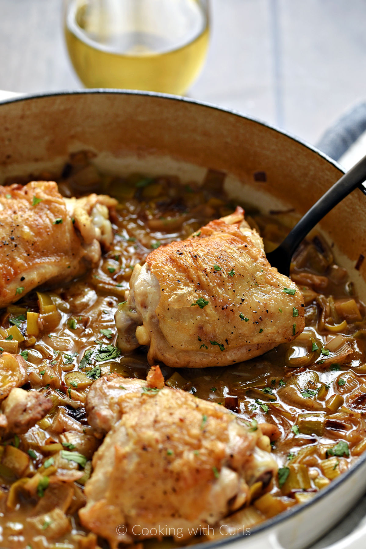 Coq au Riesling chicken thighs with Leeks in a skillet. 