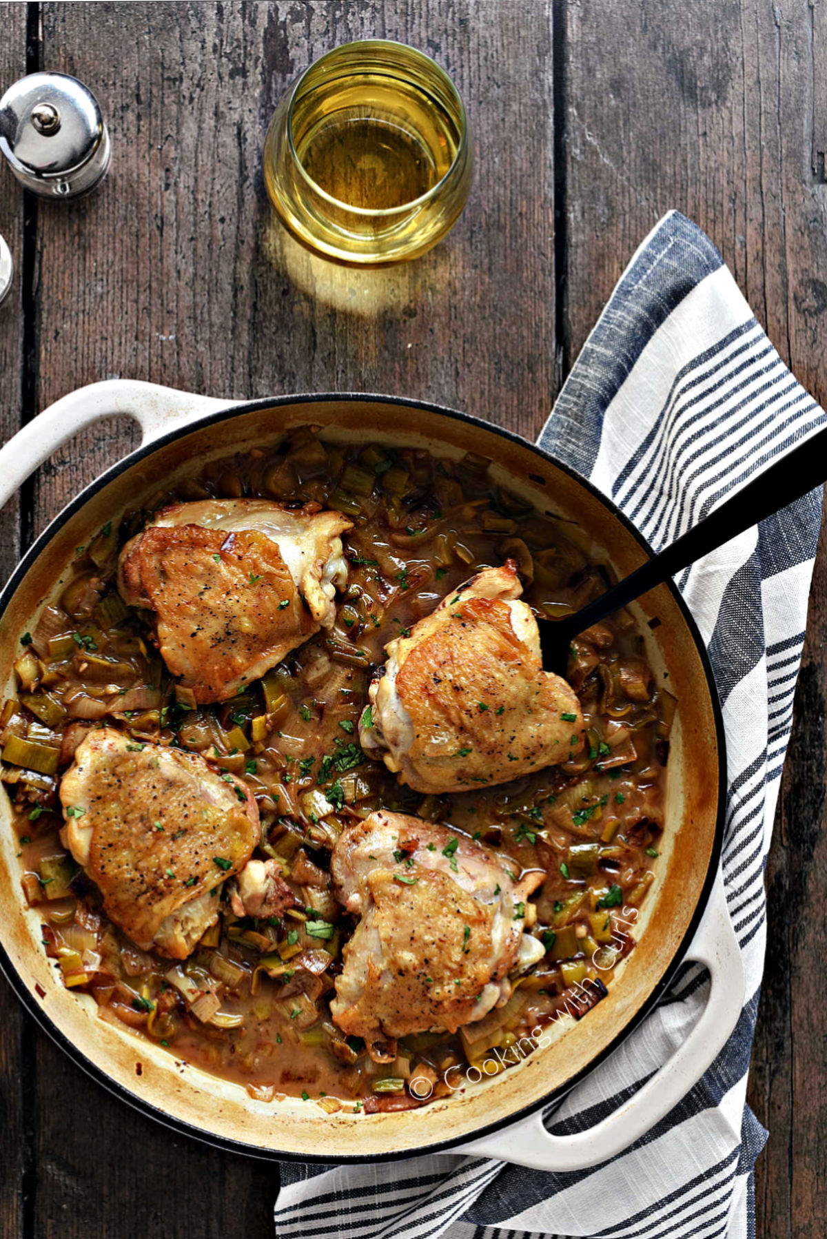 Looking down on Coq au Riesling chicken thighs with Leeks in a skillet. 