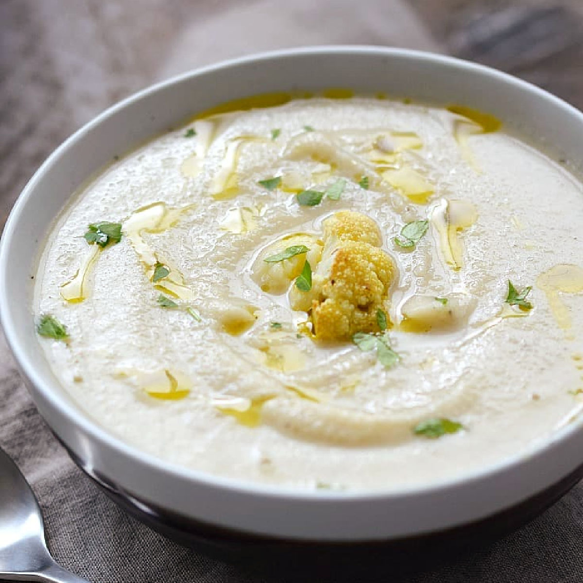 Roasted Cauliflower and Garlic Soup topped with roasted cauliflower and drizzled with olive oil. 