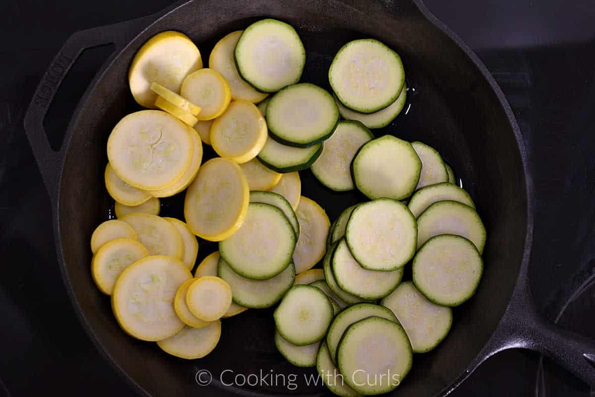Sliced zucchini and yellow squash in a cast iron skillet. 