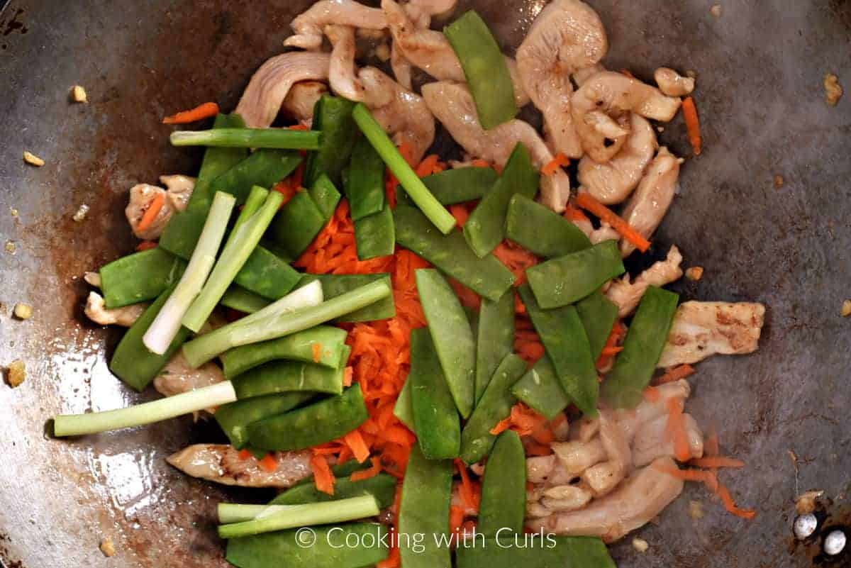 Snow peas, green onion, and shredded carrots added to the wok. 