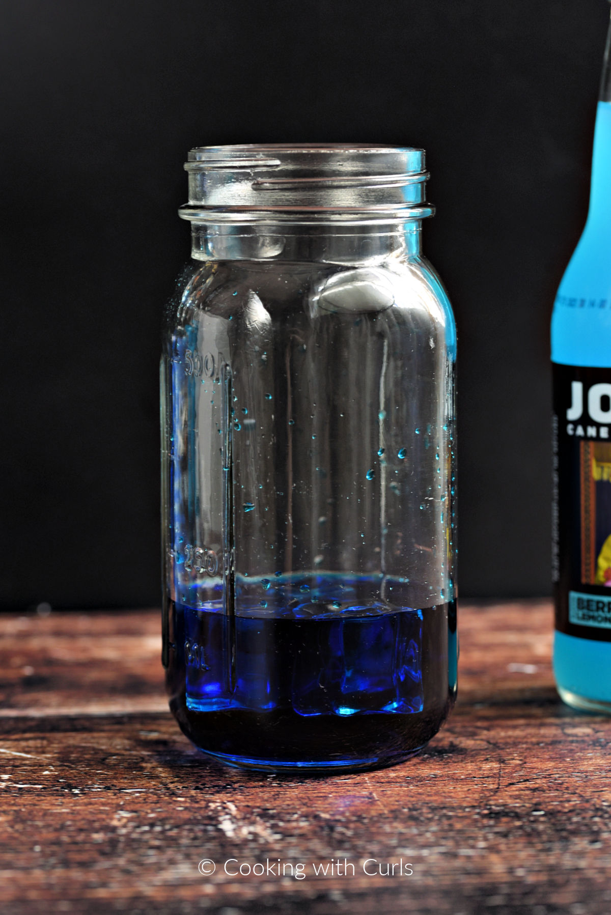 Blue vodka, blue curacao, and ice cubes in a mason jar. 