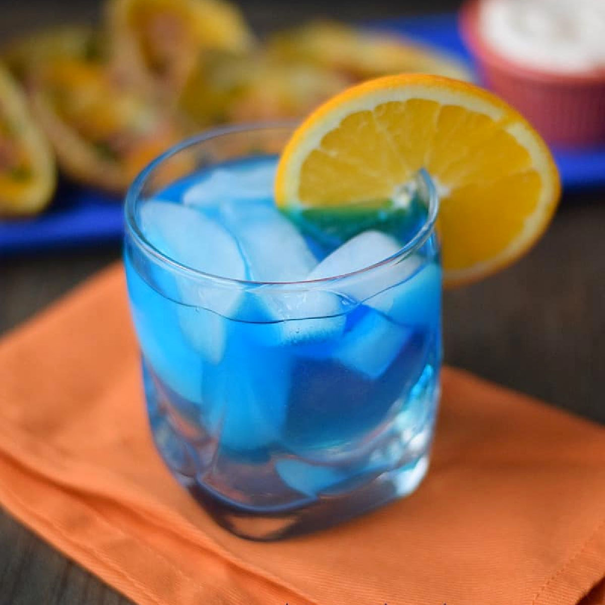 Blue cocktail with orange slice garnish.