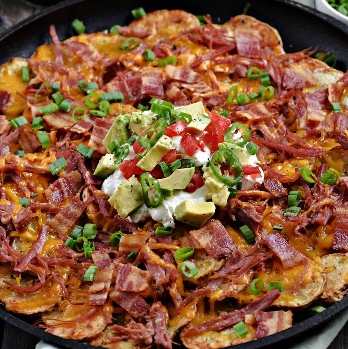Corned Beef Irish Nachos with potato slices, melted cheddar cheese, corned beef, bacon, green onions, sour cream, diced tomatoes and avocado chunks.