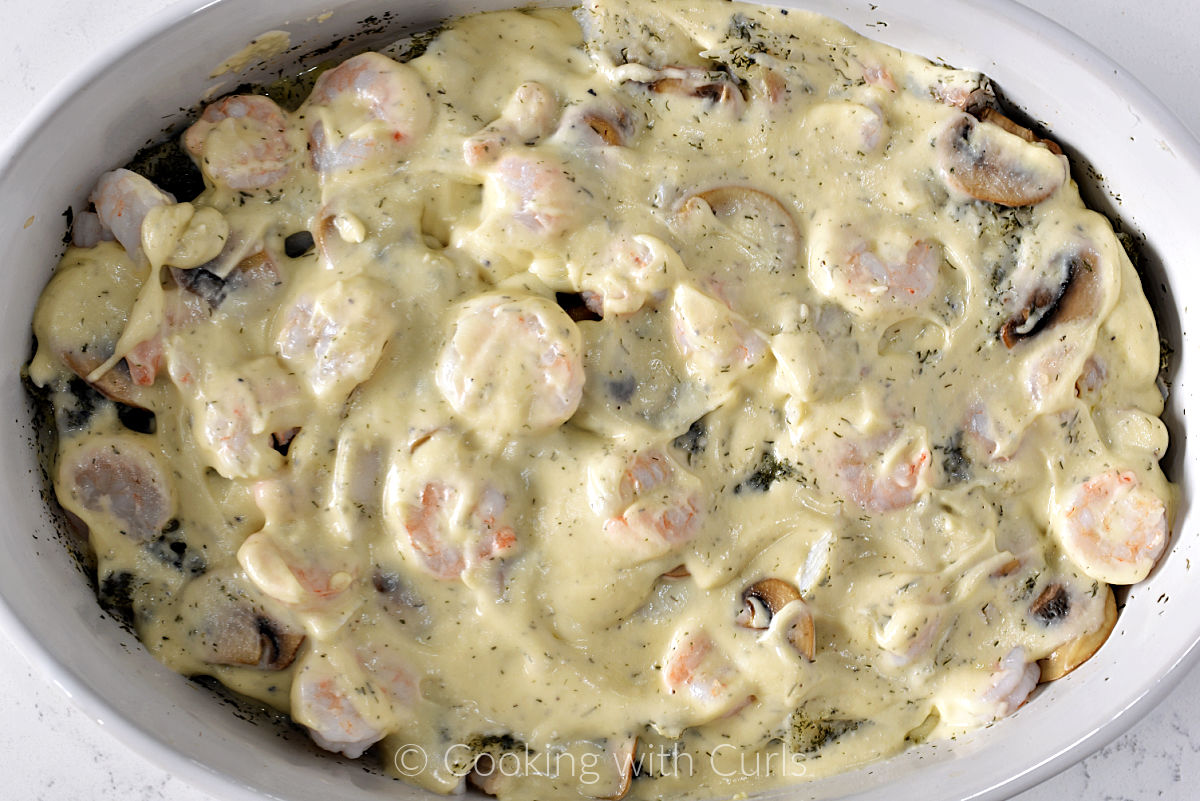 Creamy sauce spread over the top of the seafood mixture in a baking dish. 