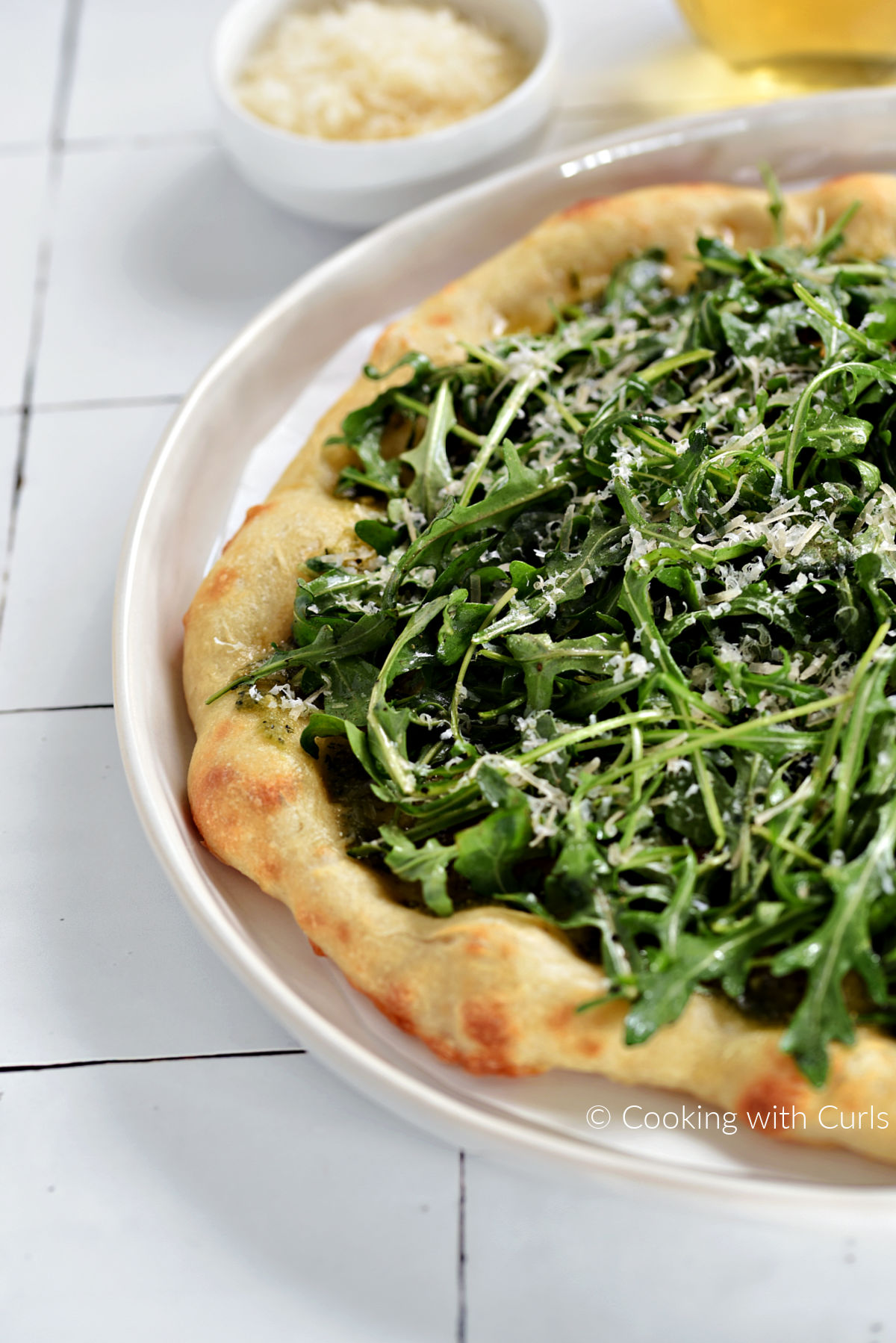 Greens Pizza Recipe with Italian crust, arugula, basil pesto, and grated parmesan cheese. 