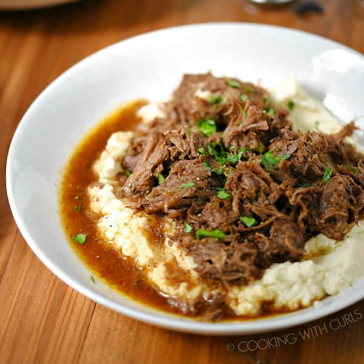 Shredded Cafe Mocha Pot Roast on a bed of mashed potatoes with gravy.