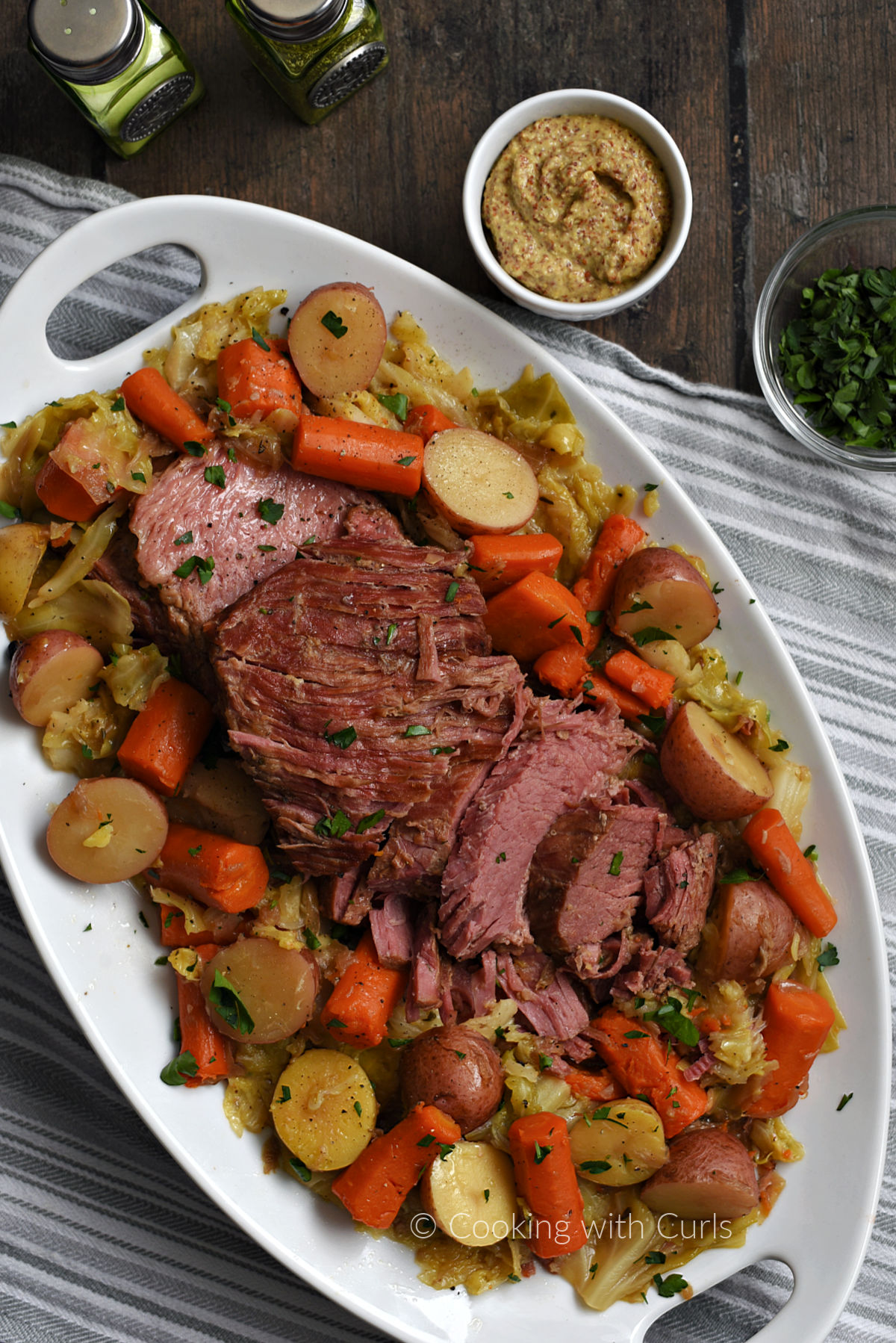 Instant Pot Corned Beef and Cabbage with potatoes and carrots garnished with chopped parsley on a serving platter.