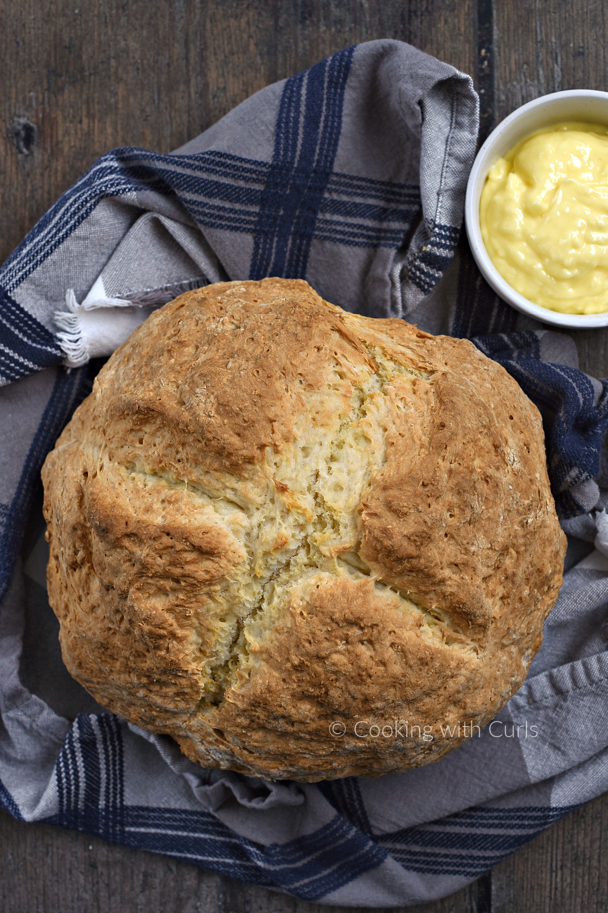Looking down on a loaf of Traditional Irish Soda Bread with a bowl of butter on the side. 