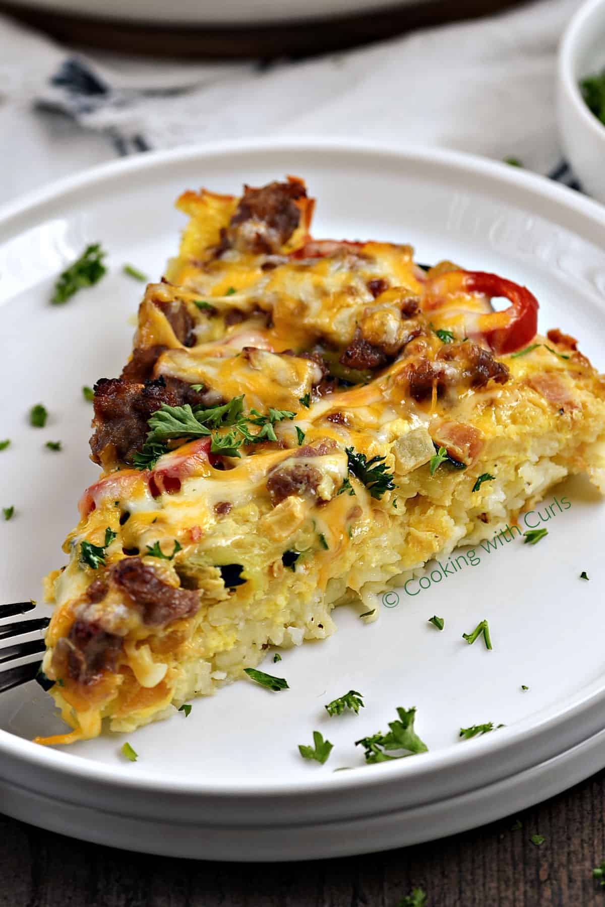 A slice of Breakfast Pizza with Hash Brown Crust topped with sausage, eggs, peppers and melted cheese. 