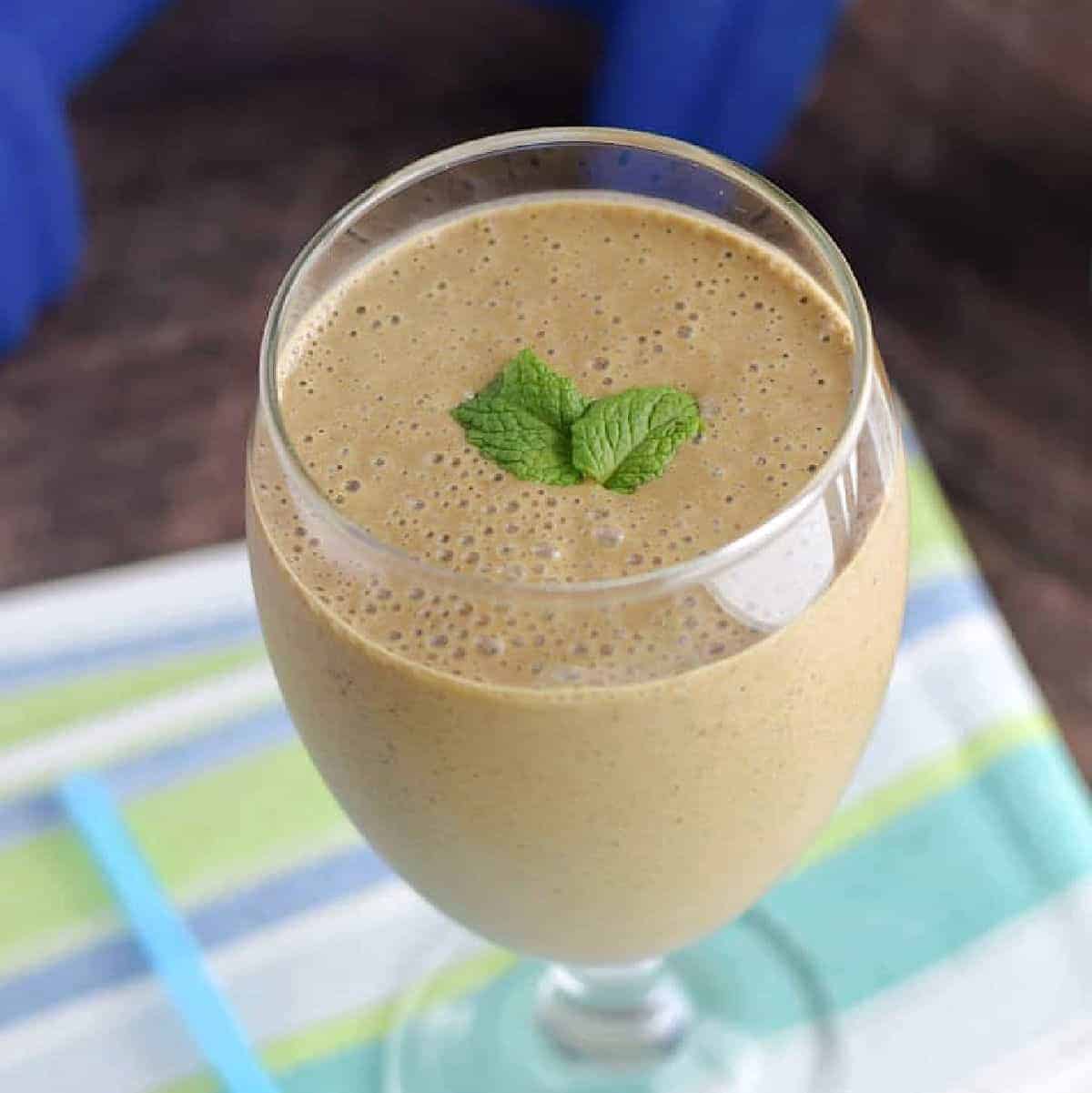 Chocolate peanut butter smoothie in a goblet glass topped with fresh mint.