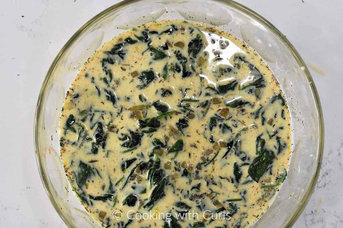 Cooked spinach and onion mixture mixed with beaten egg mixture in a large bowl. 