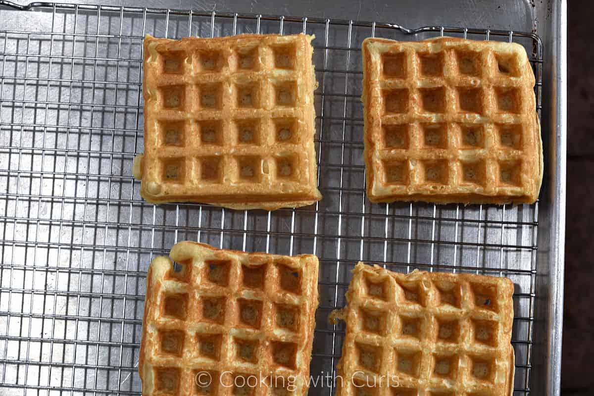 Cooked waffles on a wire rack topped baking sheet. 