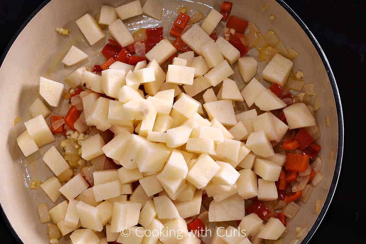 Diced onion, red pepper, garlic and potatoes in a skillet. 