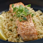 Center-cut salmon filet topped with micro-greens on a bed of risotto.
