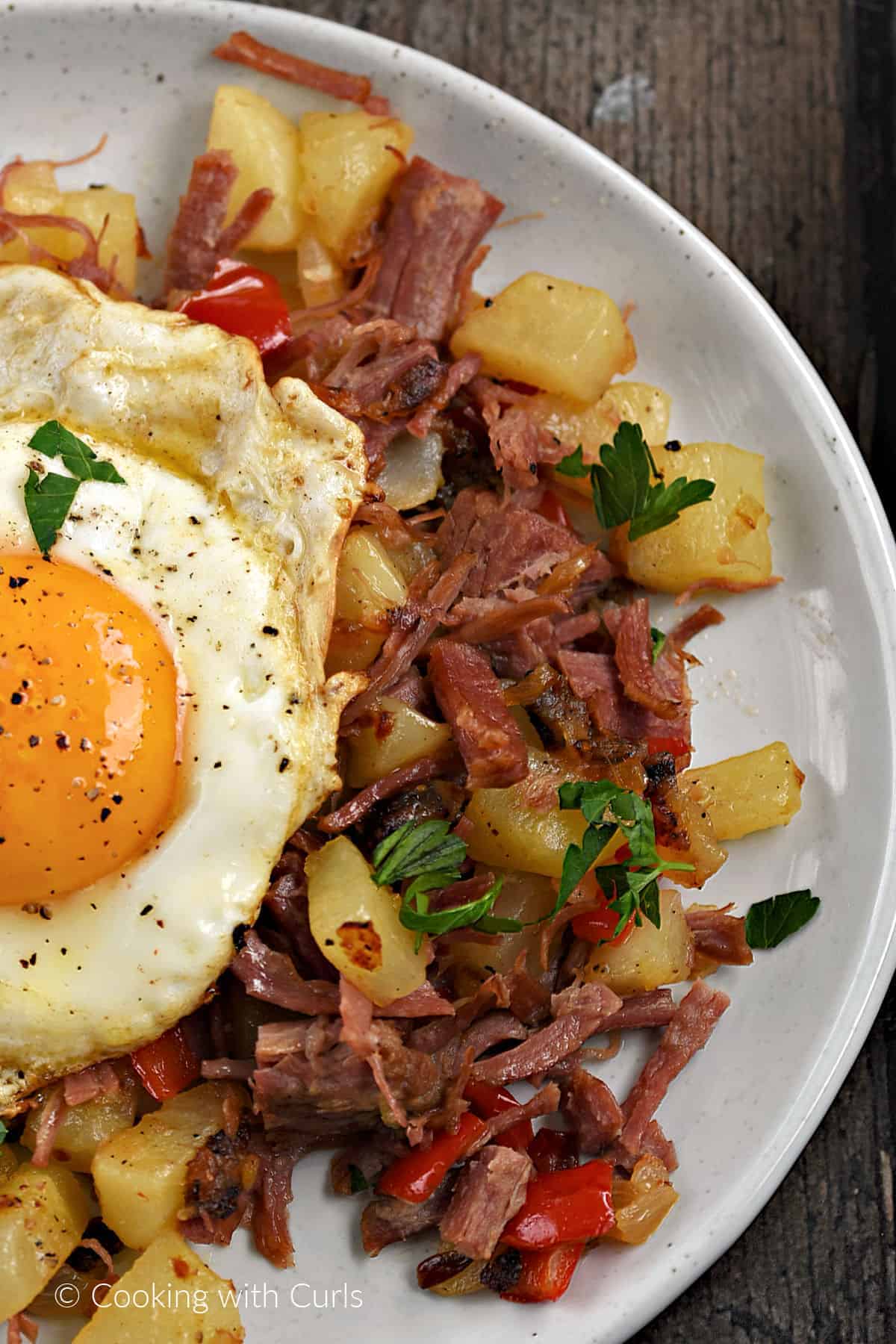 Fried egg topped corned beef hash on a plate. 
