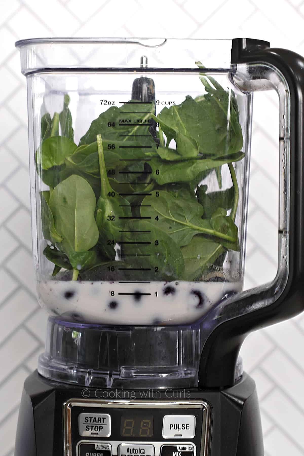 Almond milk, blueberries and spinach leaves in a blender. 