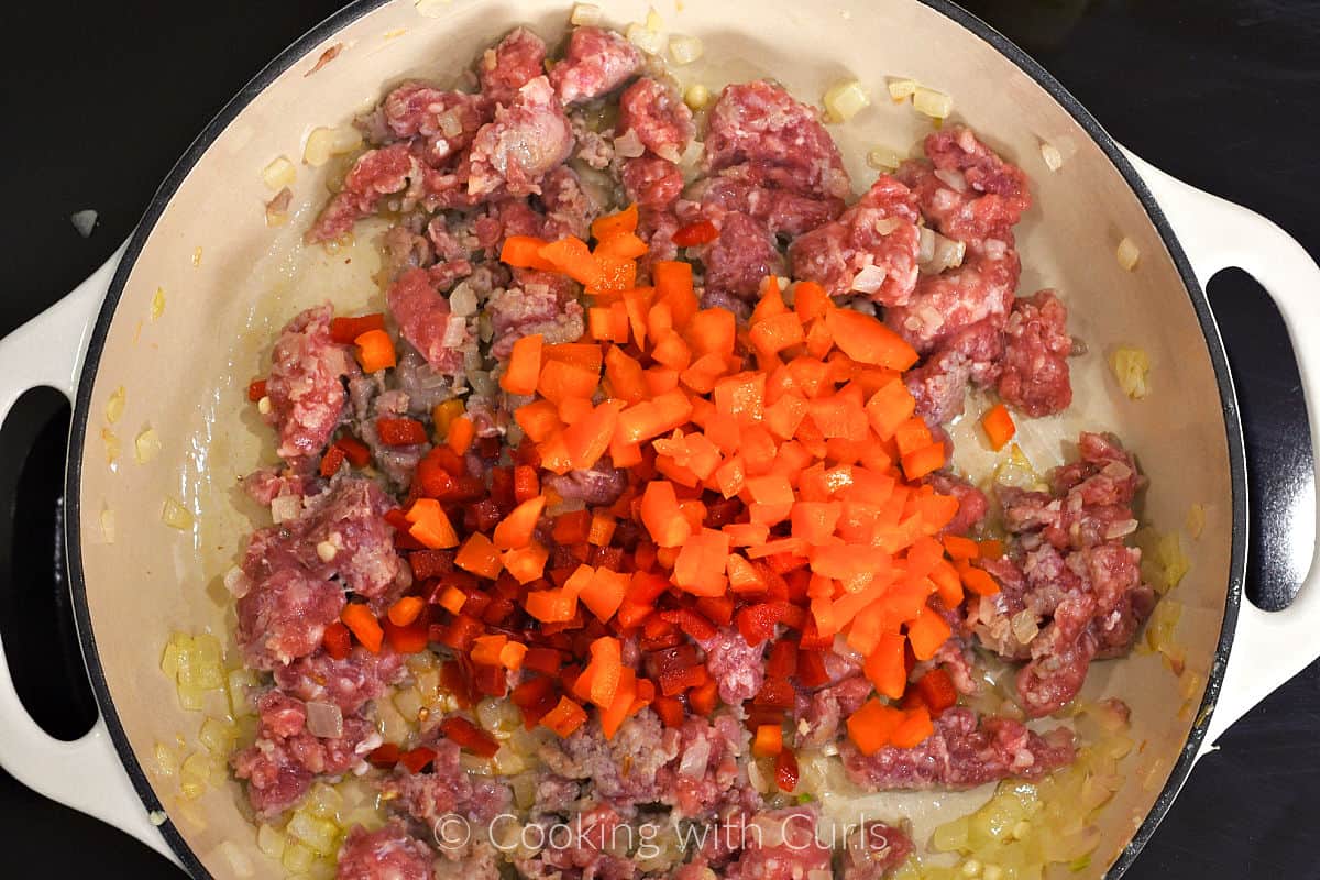 Diced red and orange pepper, onion and ground Italian sausage in a skillet. 