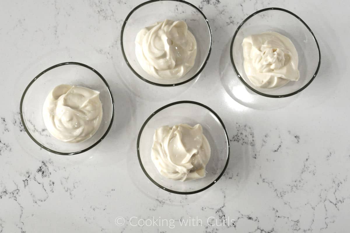 Greek yogurt in four small glass bowls.