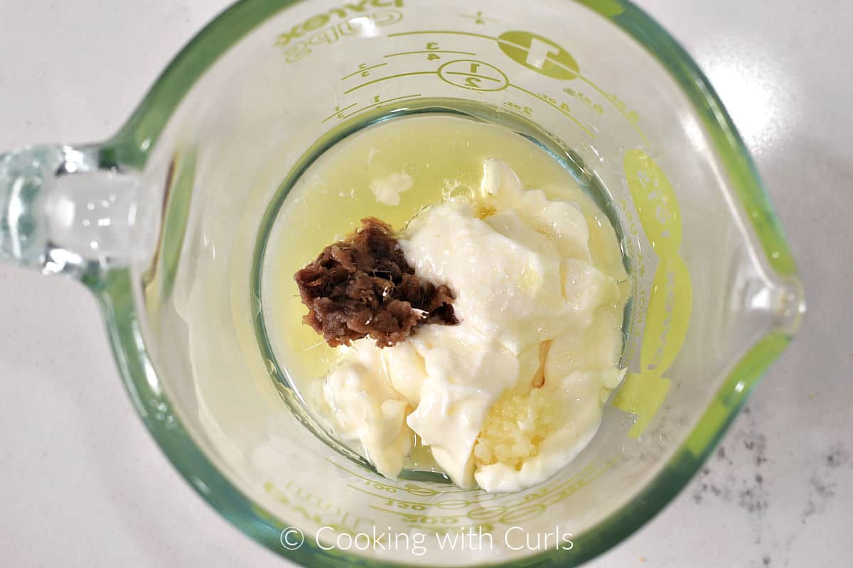 Mayonnaise, lemon juice, garlic and anchovy paste in a glass measuring cup. 