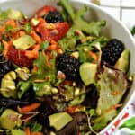 A big salad made with mixed greens, berries, avocado, pistachios and micro greens.
