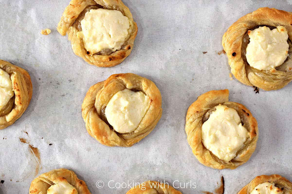 Eight cream cheese filled puff pastry swirls baked on parchment paper. 