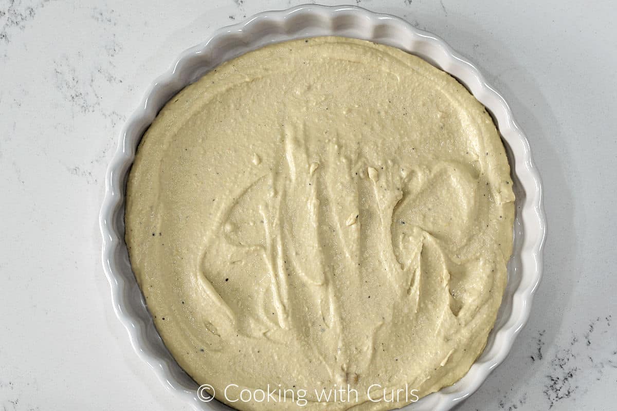 Hummus spread out in a 10-inch tart pan.