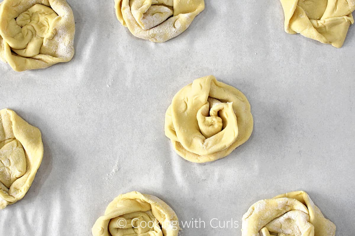 Twisted strips of puff pastry swirled into circles on a parchment lined baking sheet. 
