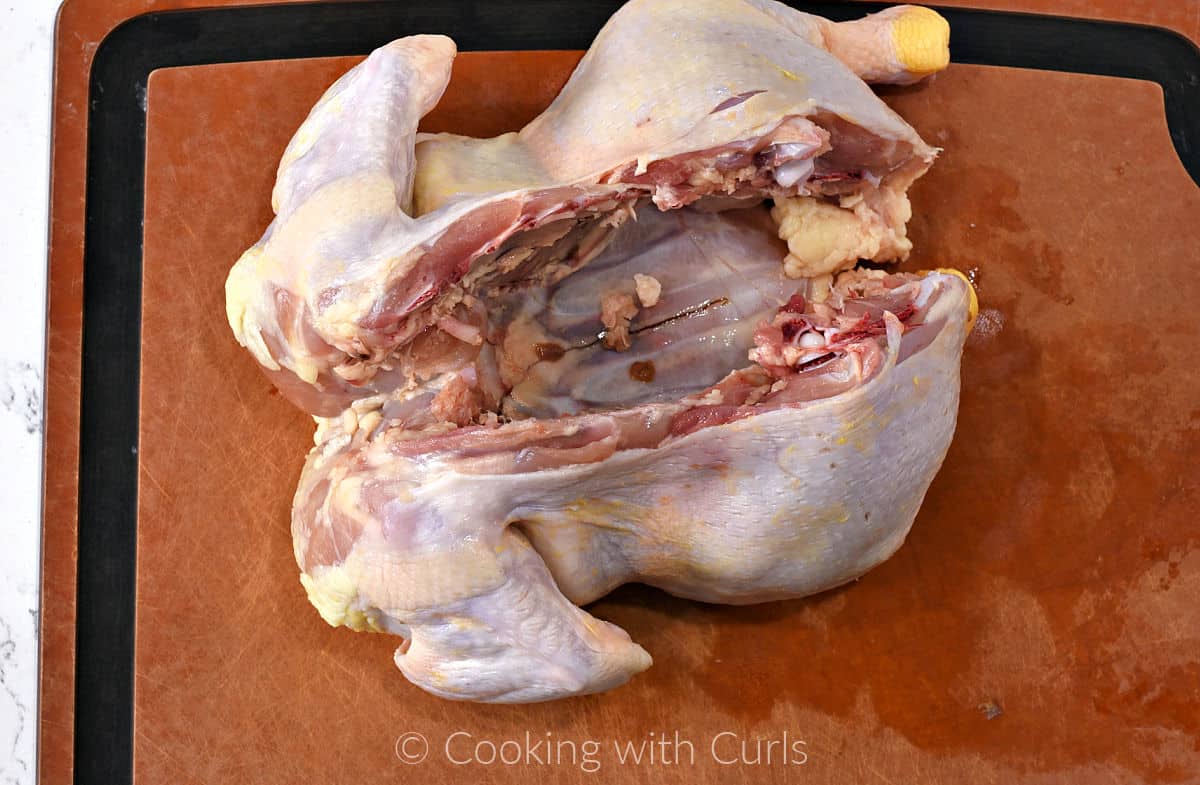 Backbone cut out of a whole chicken on a cutting board. 