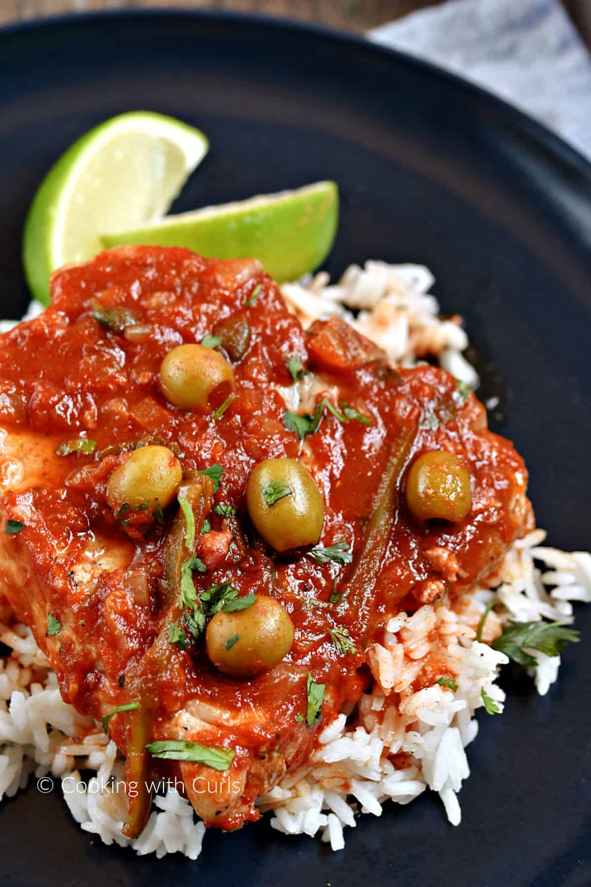 Pork Chops with Veracruz Sauce served over rice with lime wedges. 