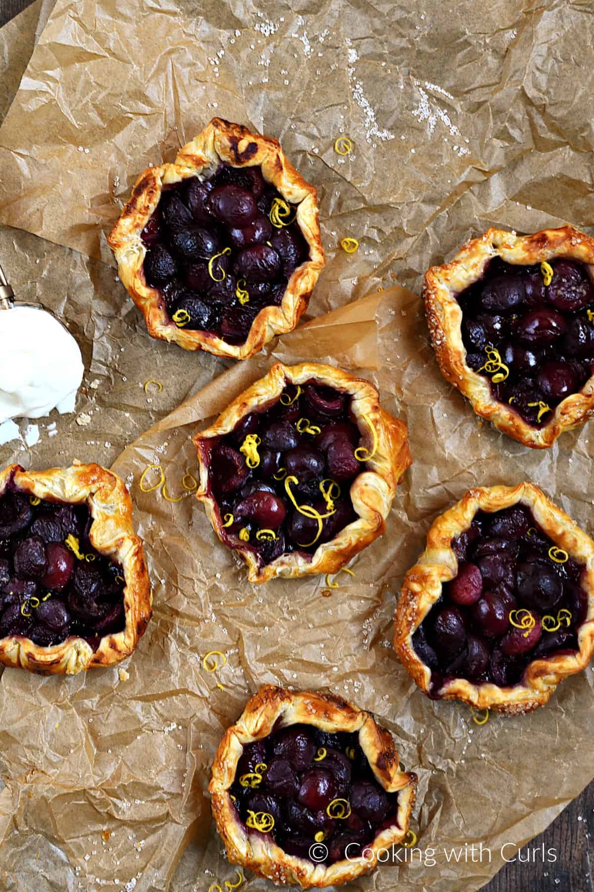 Six puff pastry tart shells filled with cherries.