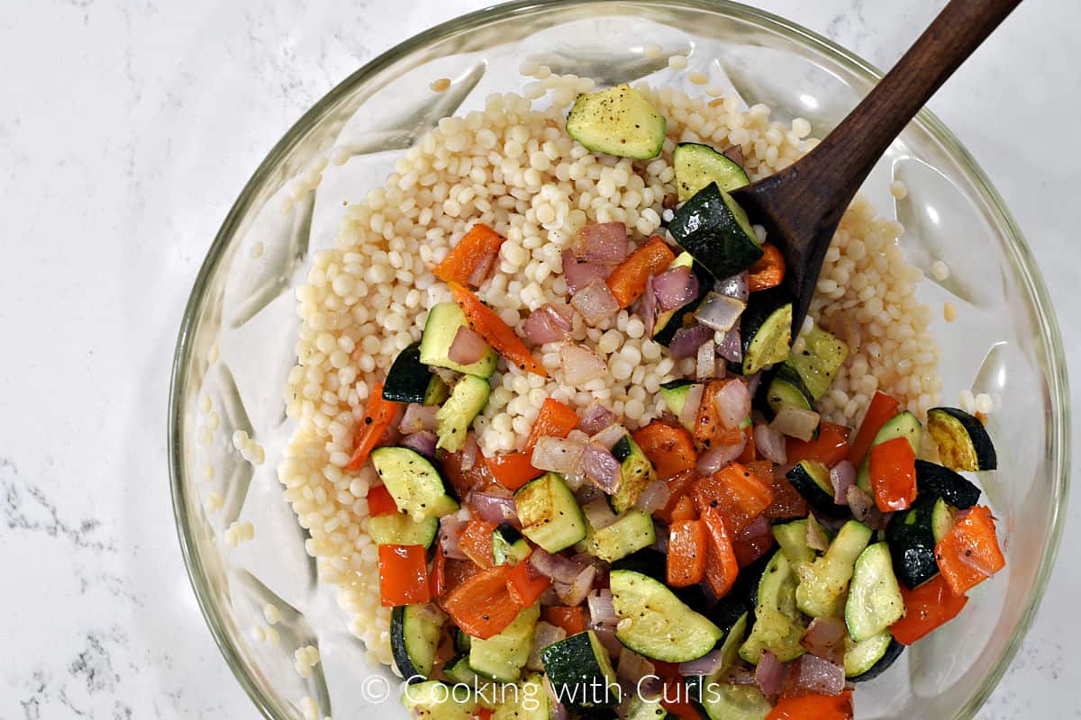 Cooked couscous and roasted vegetables in a large mixing bowl. 